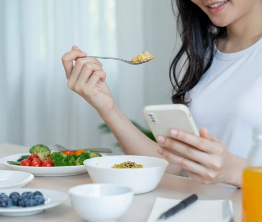 Woman eating healthy and looking at phone